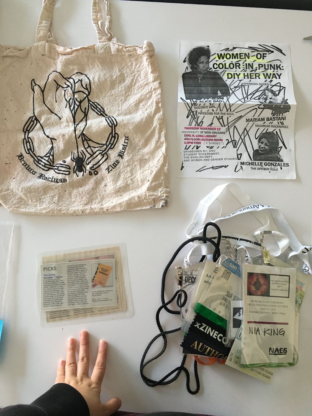 photo of a Brown Recluse Zine Distro tote, an event flyer, and a bag of conference badges