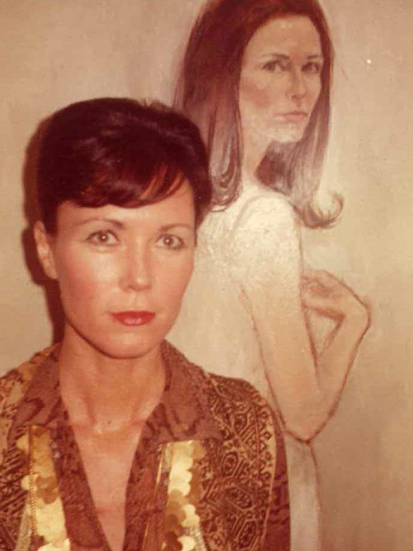 Nancy Friday stands before a painted portrait of herself